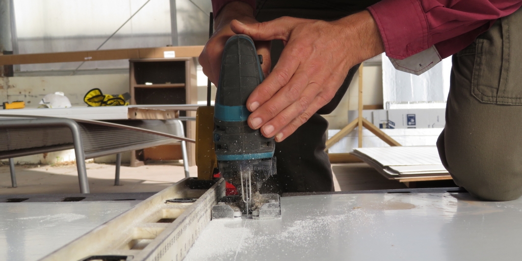 Kai Staats using a reciprocating saw to cut a wall panel for the SAM Workshop at Biosphere 2.