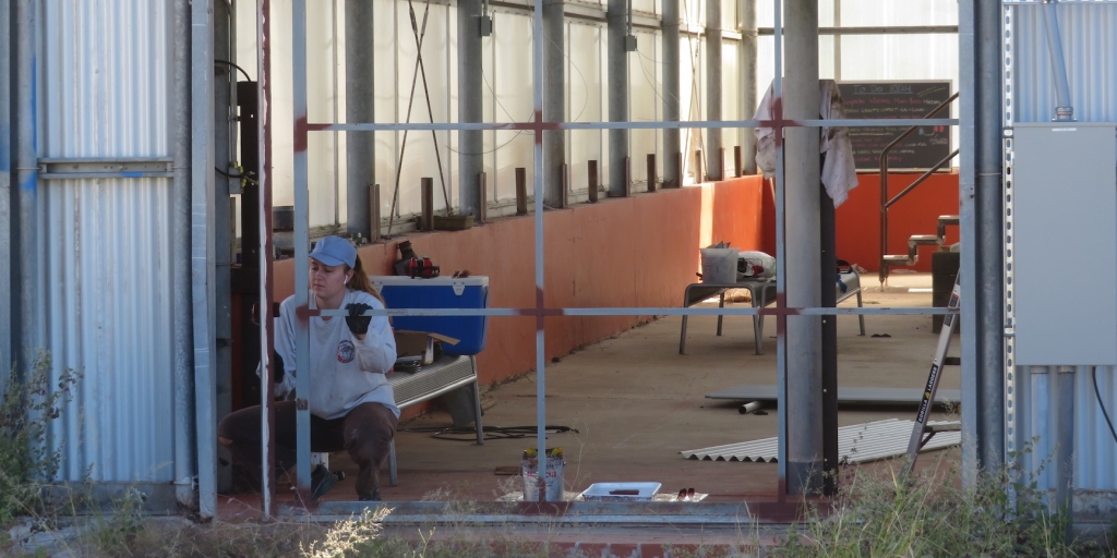 Luna Powell painting the sliding door of the Mars yard at SAM